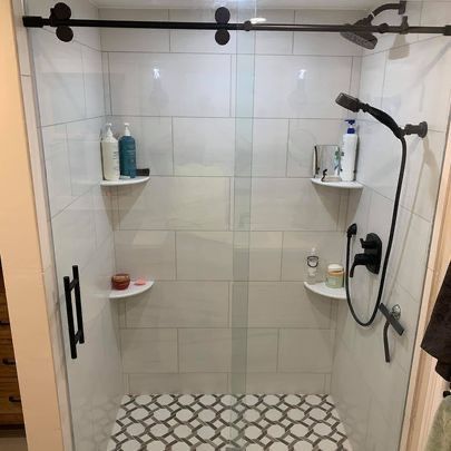 A shower with a sliding glass door and a shower head.