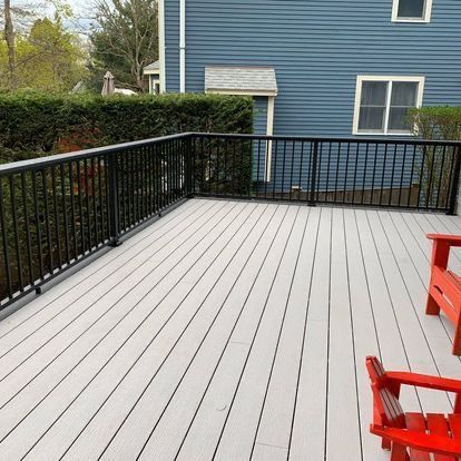 A white deck with red chairs and a blue house in the background