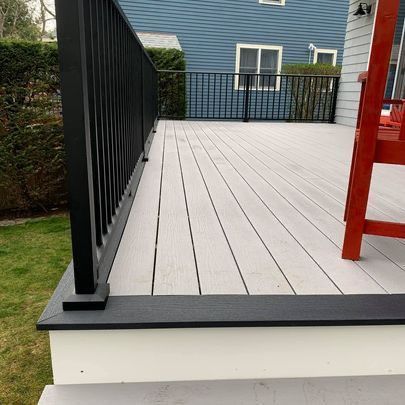 A white deck with a black railing and a red chair on it.