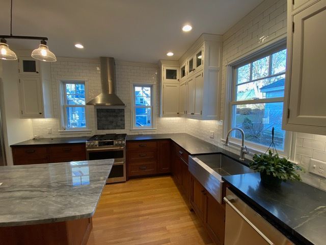 A kitchen with a sink , stove , cabinets and a window.