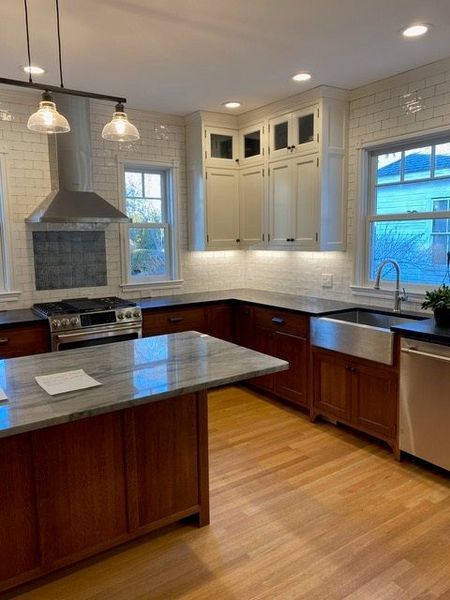 A kitchen with a large island , stove , sink and dishwasher.