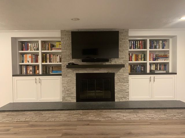 A living room with a fireplace , bookshelves , and a flat screen tv.
