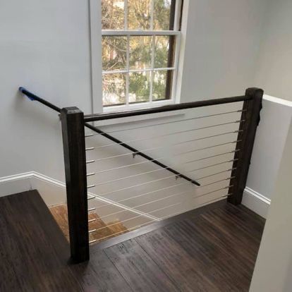 A staircase with a wire railing and a window.
