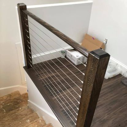 A staircase with a wooden railing and stainless steel wire railing.