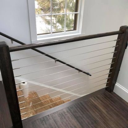 A staircase with a stainless steel railing and a wooden handrail.