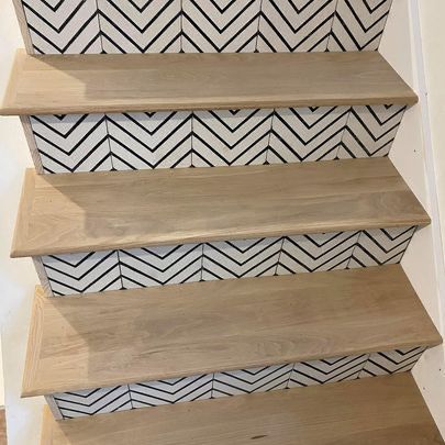 A wooden staircase with a black and white chevron pattern on the steps.