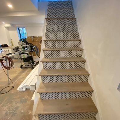 A staircase with a geometric pattern on the steps is being built in a basement.