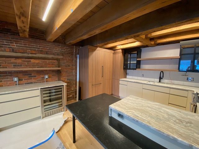 A kitchen with a brick wall and wooden beams.