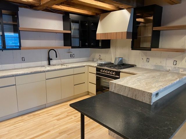 A kitchen with white cabinets and a black counter top