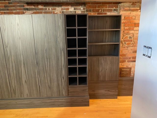 A room with a brick wall and wooden cabinets and shelves.