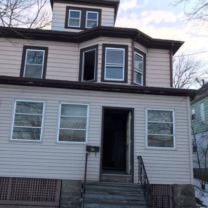 The front of a house with a lot of windows and stairs leading up to it.
