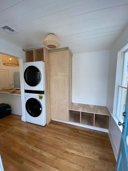 A laundry room with a washer and dryer stacked on top of each other white wall.