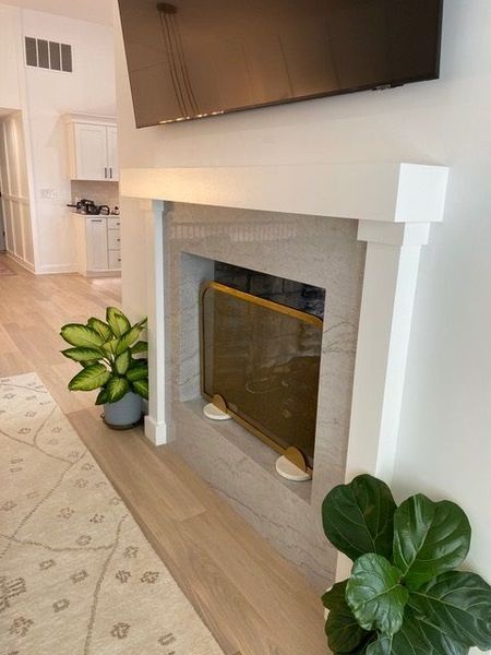 A living room with a fireplace and a tv on the wall.