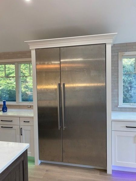 A stainless steel refrigerator in a kitchen with white cabinets