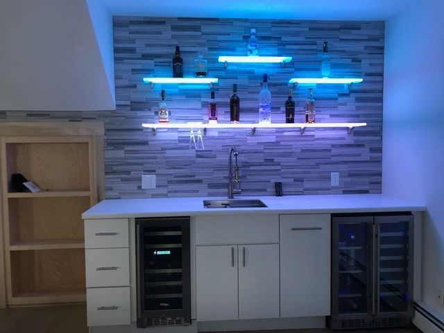 A kitchen with a sink and shelves with bottles on them