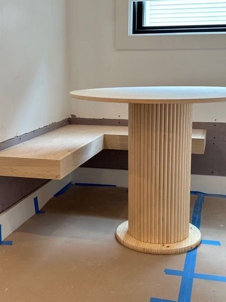 A wooden table with a bench underneath it in a room.
