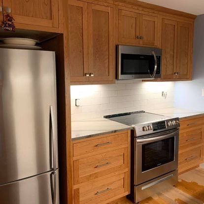 A kitchen with wooden cabinets , stainless steel appliances , and a refrigerator.