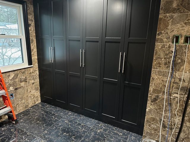 A room with a lot of black cabinets and a window.