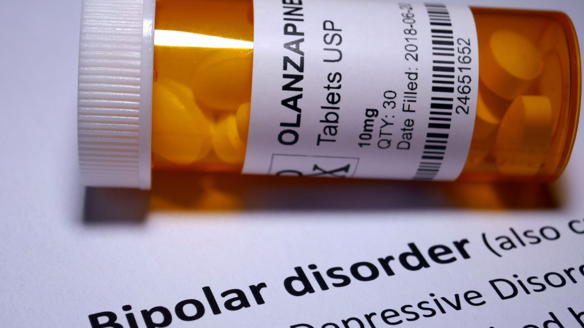 A bottle of medicine tablets sits on a piece of paper