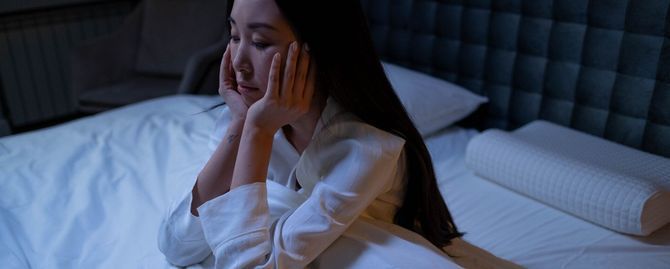 A woman is sleeping in a bed with white sheets and pillows.