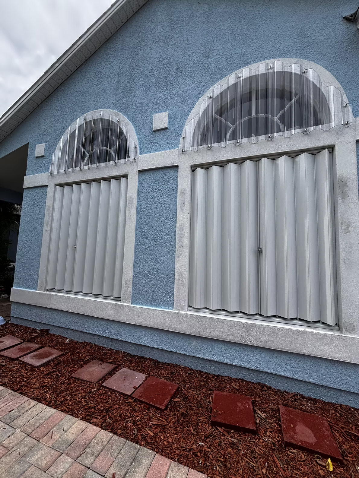 A man is installing blinds on a window in a living room.