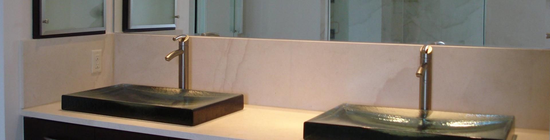 A double vanity bathroom counter featuring two rectangular vessel sinks with silver faucets against a large wall mirror.