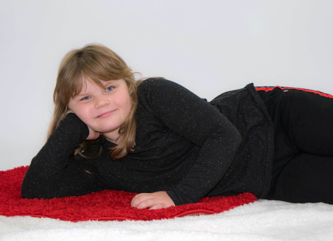 Kind Teenager Mädchen rot Teppich schwarz Kleidung blond rundlich liegend aufstützend seitlich