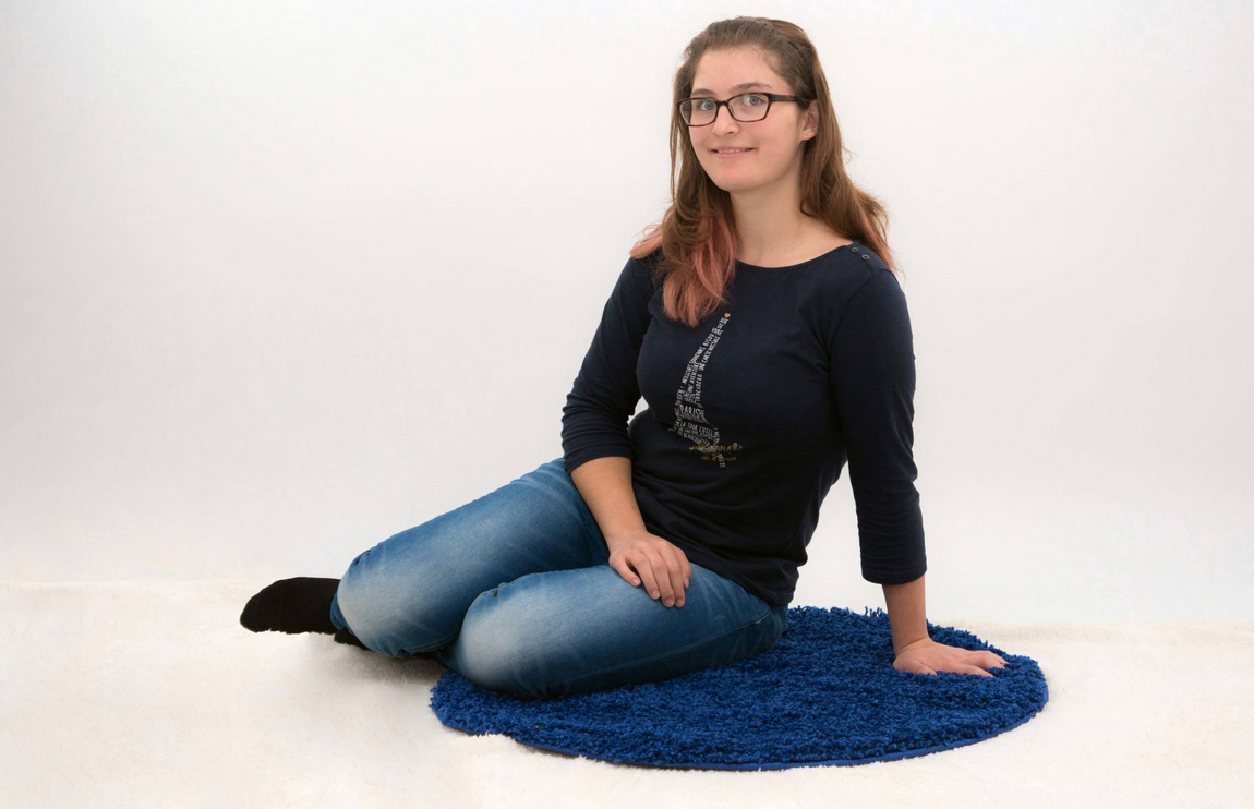 Kind Teenager Mädchen blau Shirt Teppich Jeans Lachen Brille