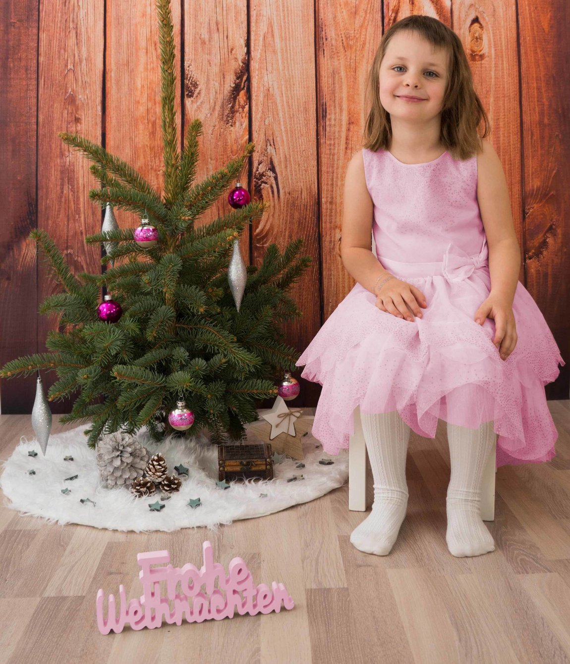Weihnachten Mädchen Weihnachtsbaum Tanne Baumschmuck Christbaum Kind Kugeln Kleid Hintergrund Holz braun Kleid rosa lachen