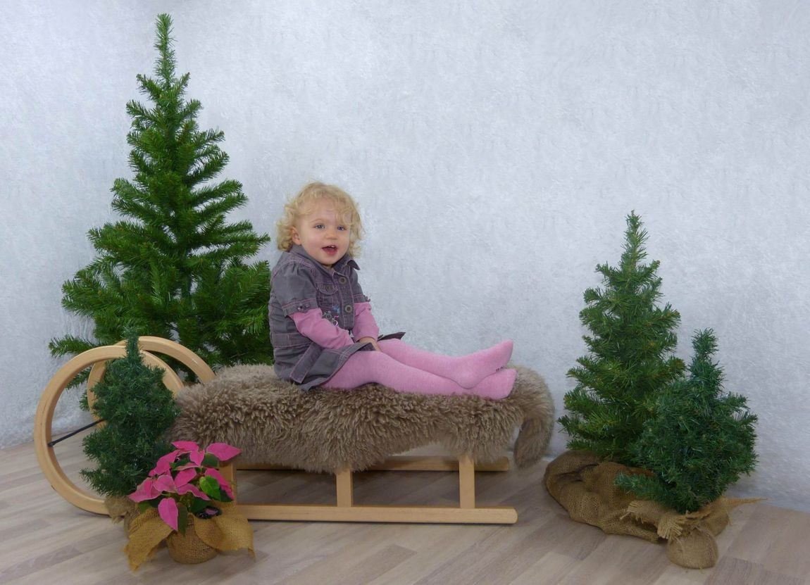 Kleinkind Kind Mädchen rosa Kleid Schlitten Baum Kunstbaum Tannenbaum Weihnachtstern Kleid Jute Lachen Spaß Shooting