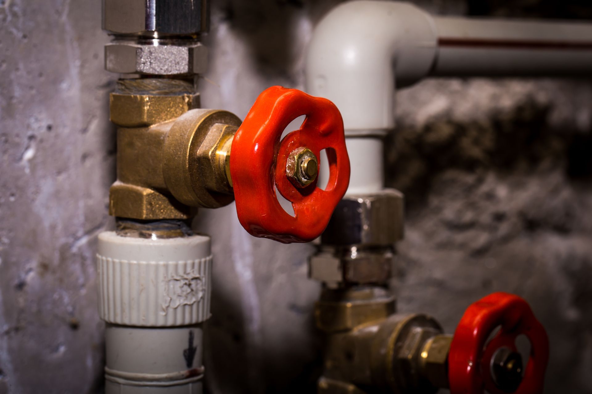 Red valve handles on metal pipes in a dim industrial setting