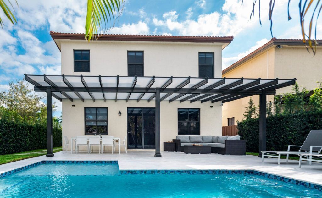 Back of a two-story beige house with a pool, patio, and pergola.