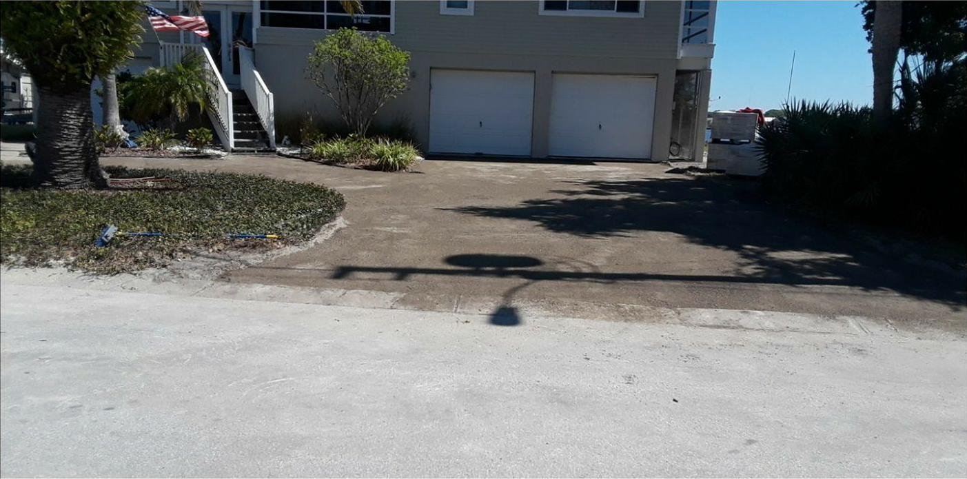 A house with a two-car garage, driveway, and landscaping on a sunny day.