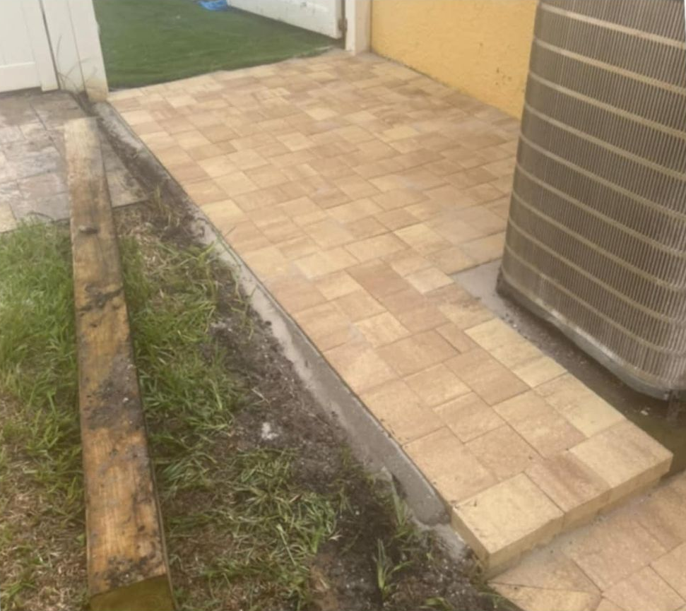 Brick patio with ramp leading to yard, next to air conditioning unit.