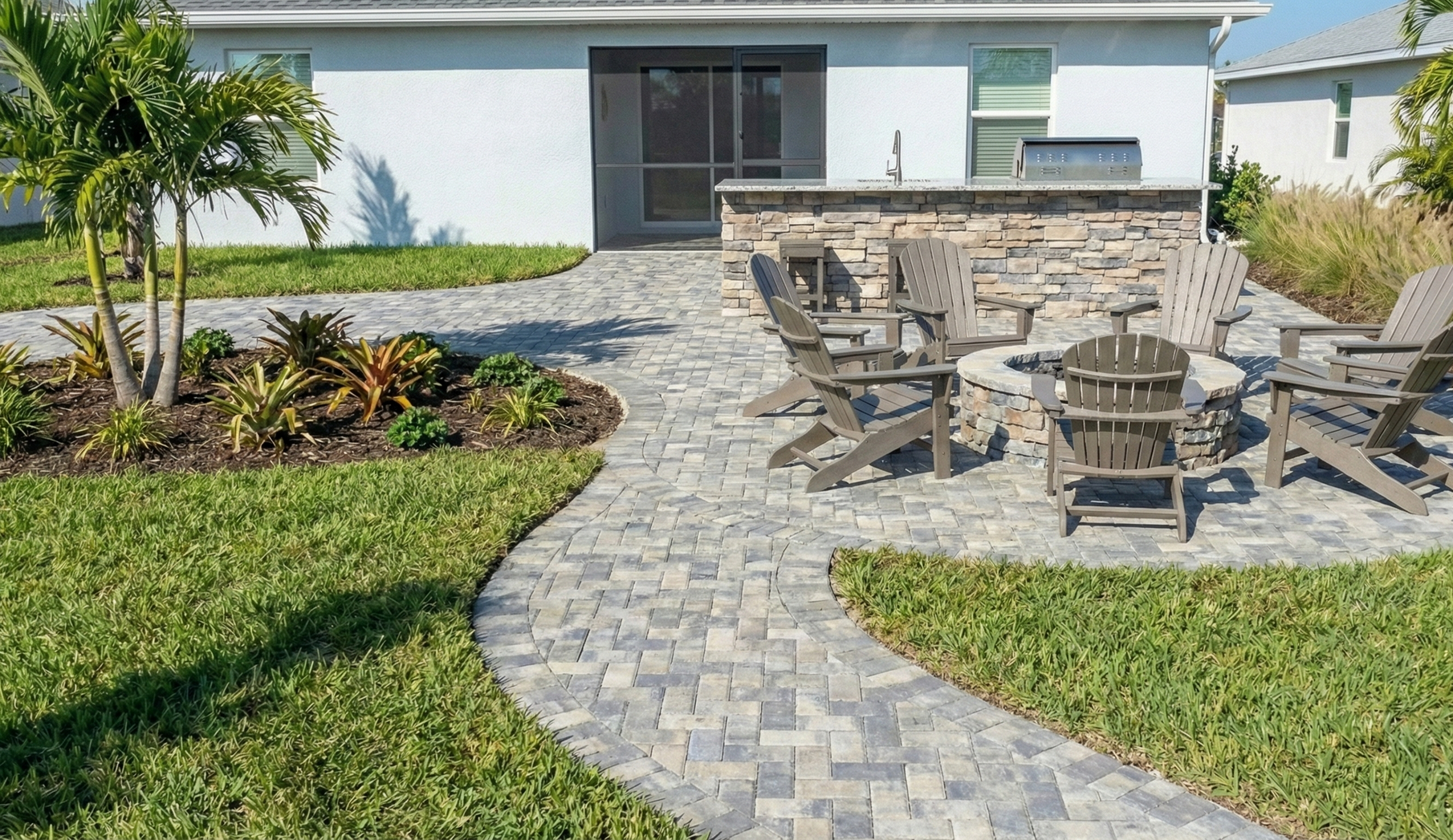 Paver walkway curves past a rock garden and connects to a driveway.