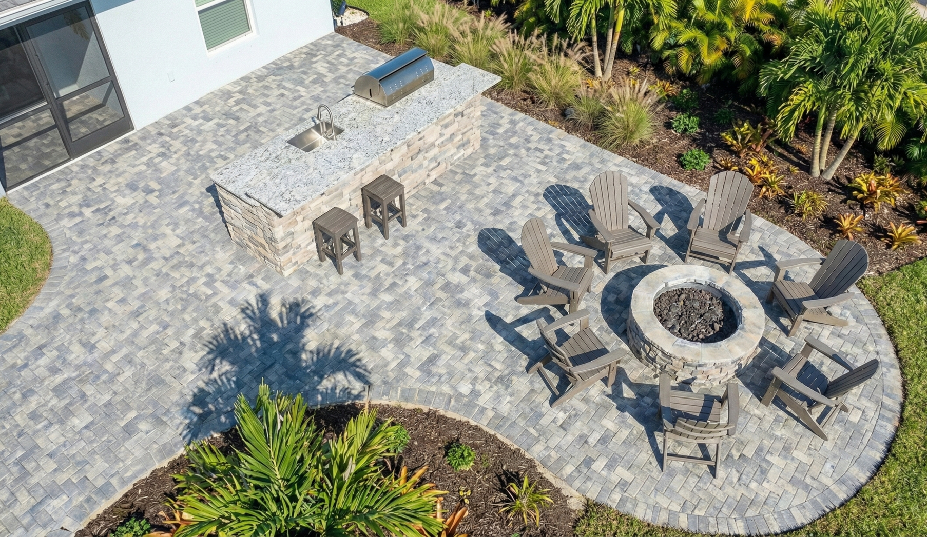 Brick driveway in mottled earth tones leads to a white stucco house with arched windows and bicycles parked in front.