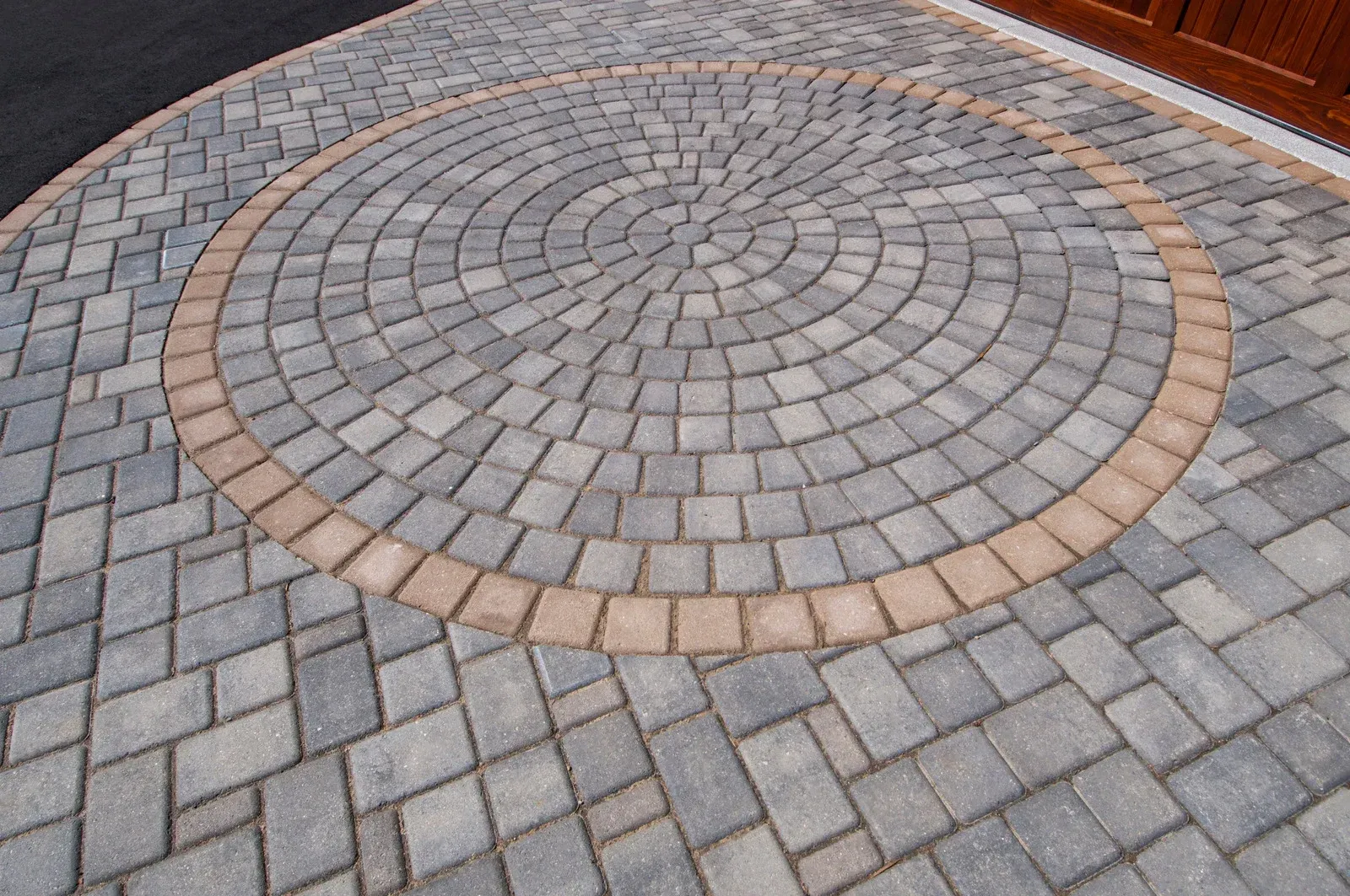Brick paved driveway with a circular pattern and light brown border.