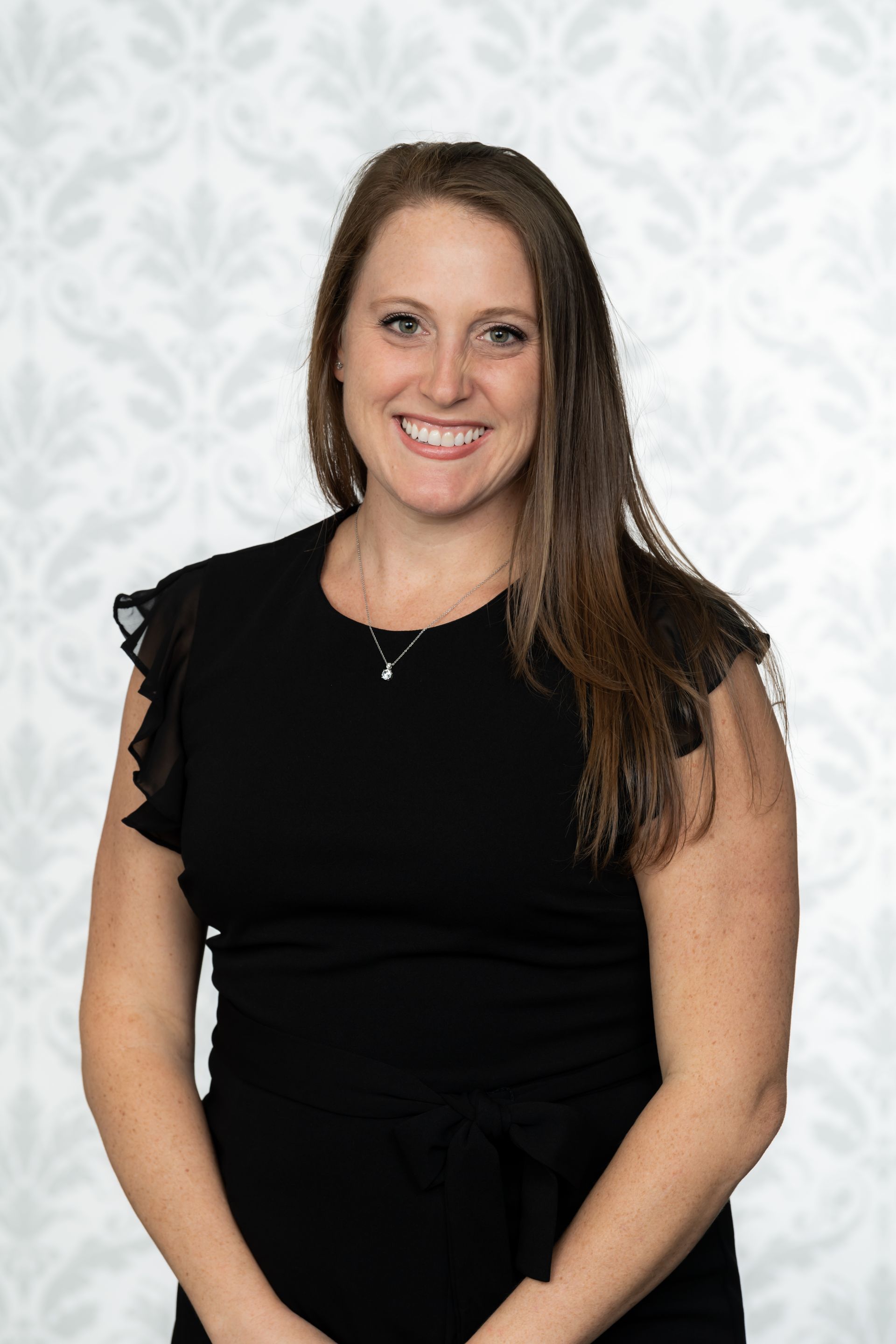 A woman in a black dress is smiling for the camera.