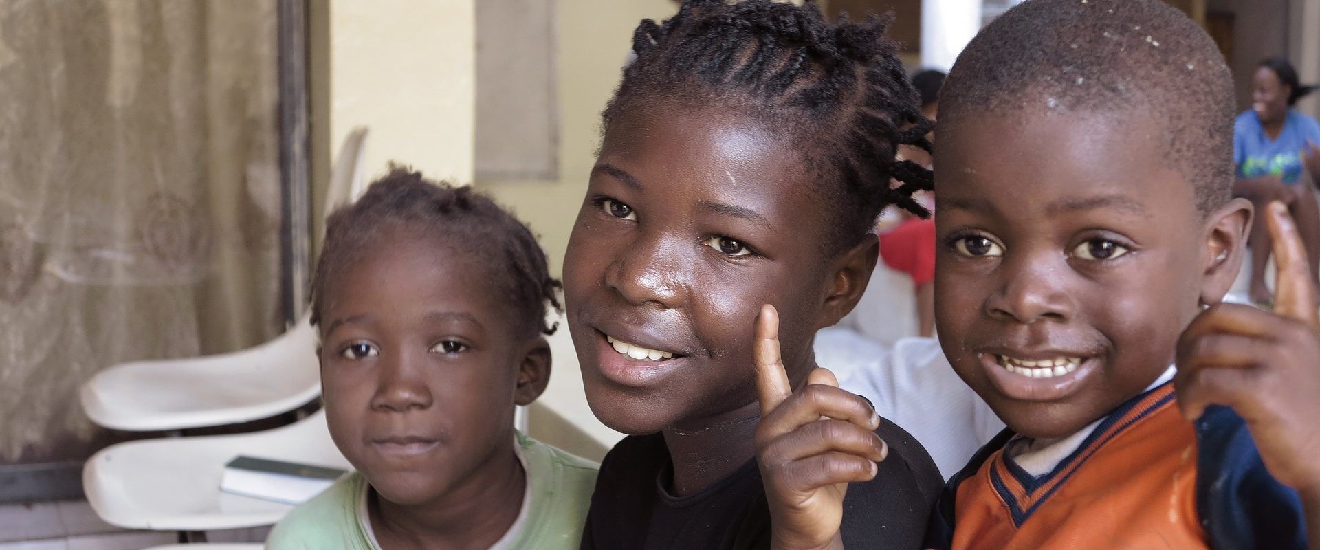 three children are posing for a picture and one of them is pointing up .