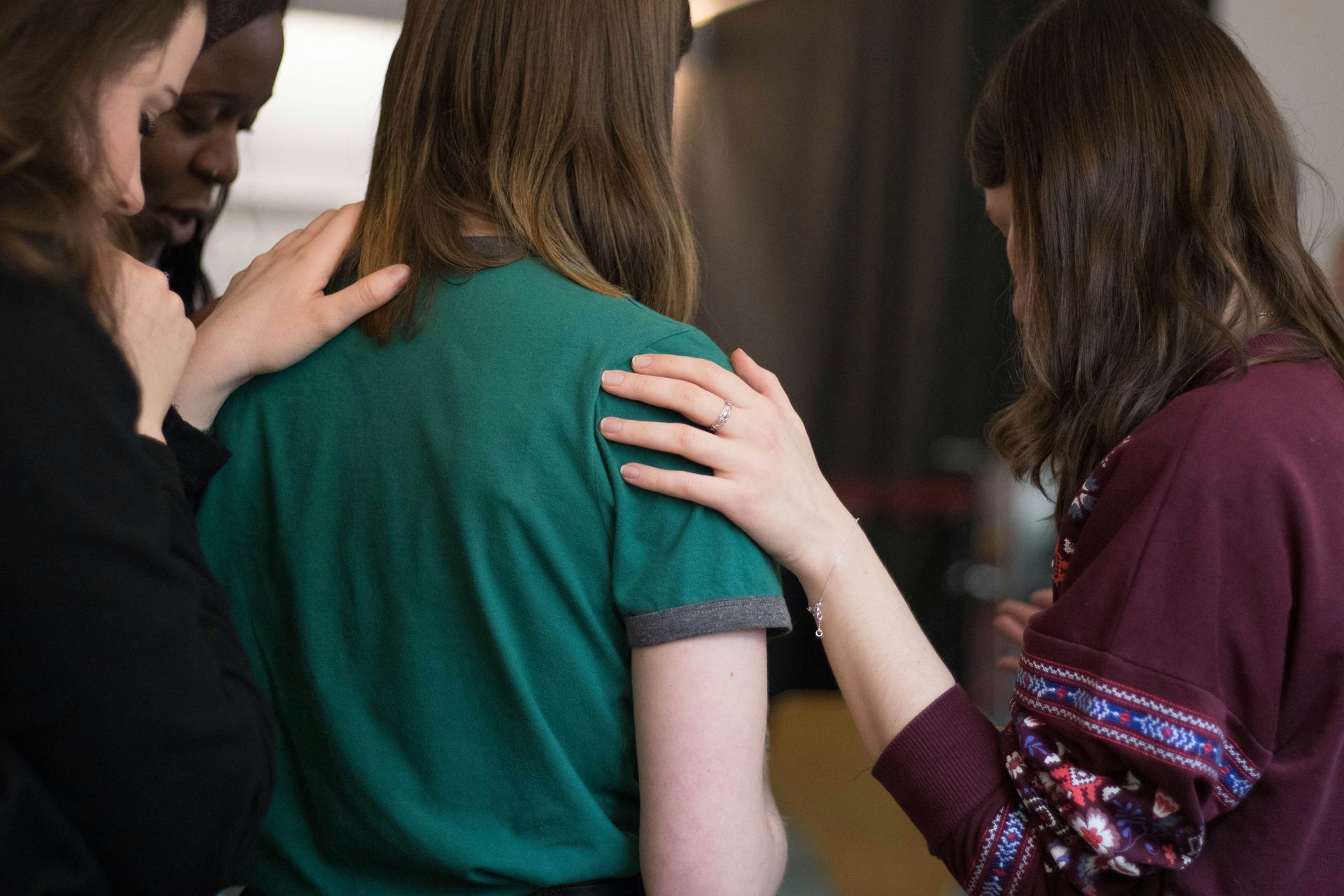 a group of women are standing next to each other with their hands on each other 's shoulders .