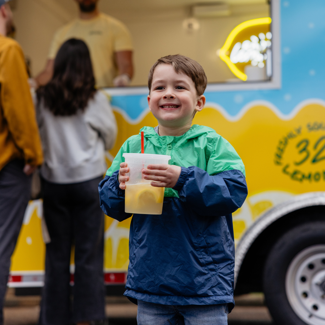 Four cups of lemonade with green straws in them