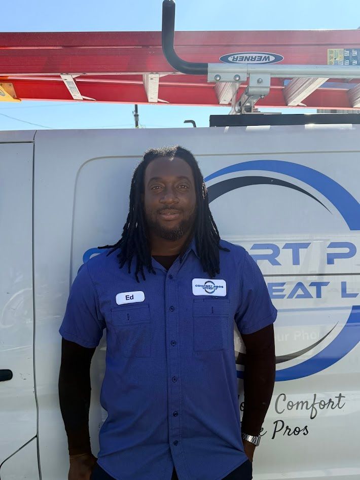 Person in a blue work shirt standing beside a white utility vehicle.
