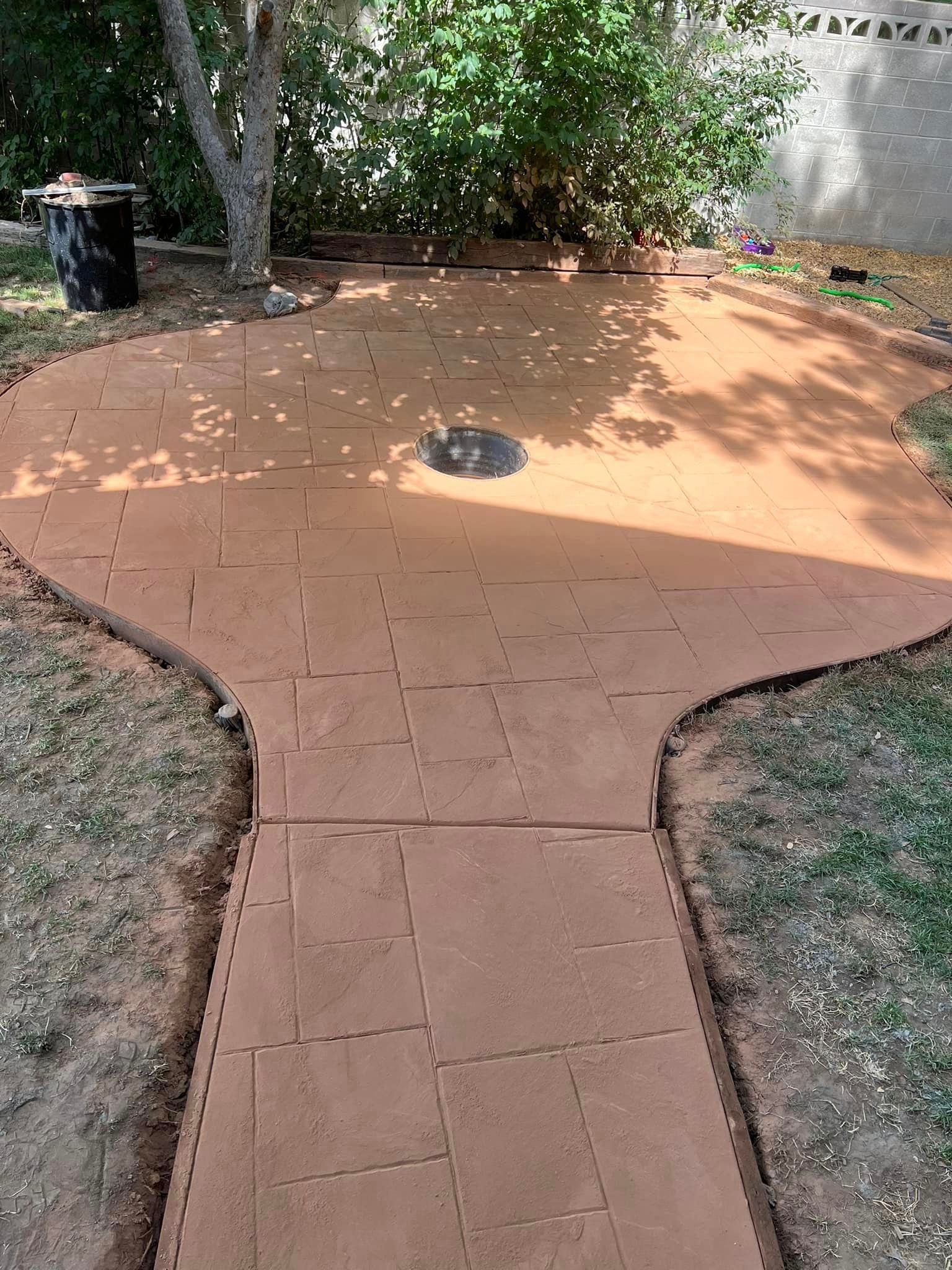 A brick walkway leading to a patio in a backyard.