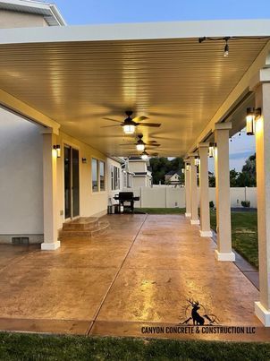 A large covered patio with a ceiling fan and lights.