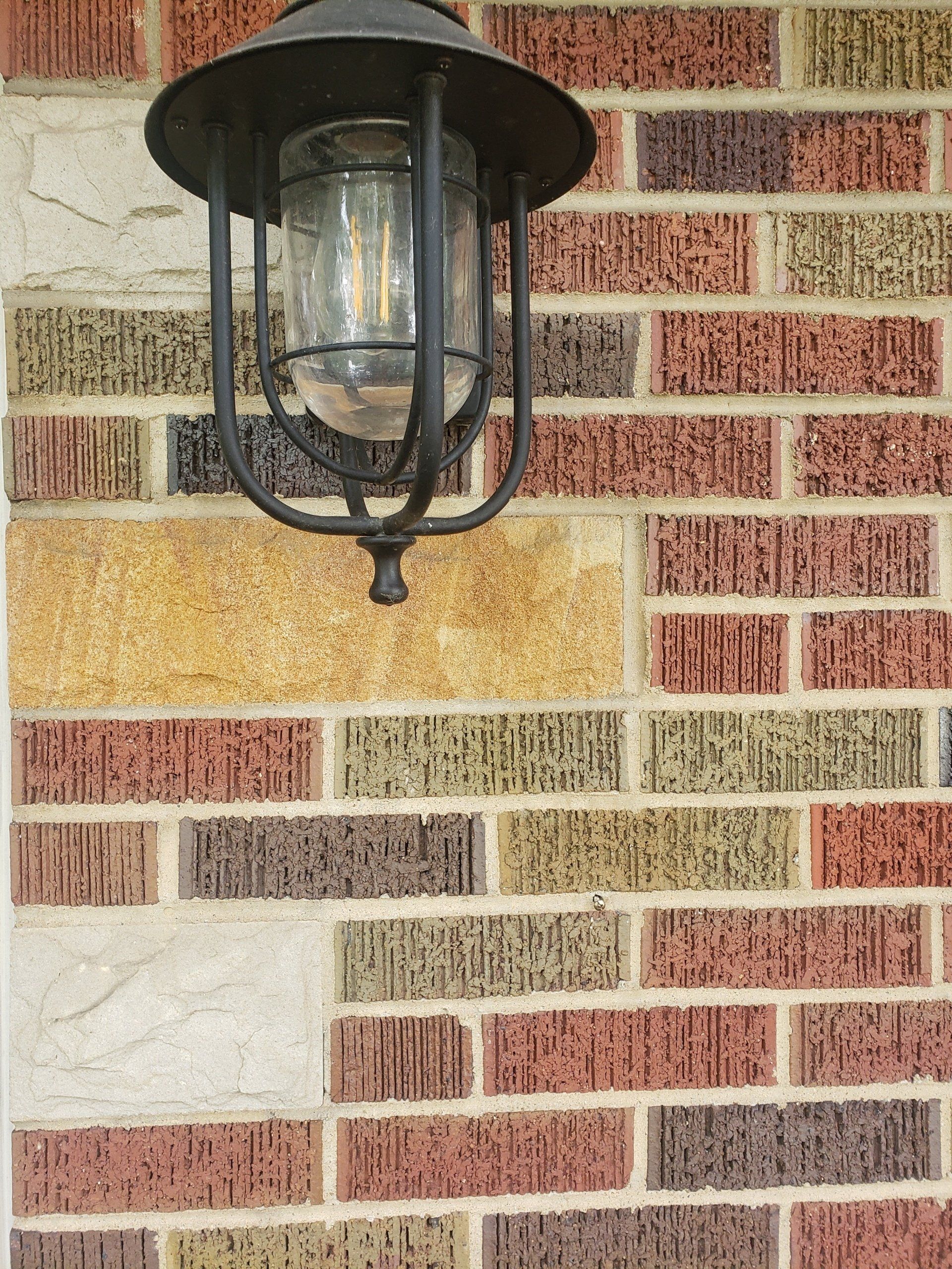 A porch lamp on a beautiful, clean brick and stone wall