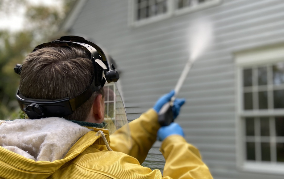 Man in PPE power washing the side of a home in Akron Ohio