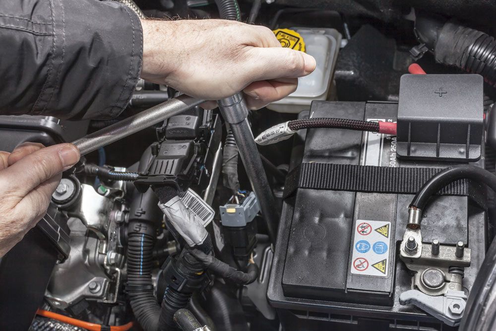 A Person Is Working on A Car Battery with A Wrench — Bob Kolln Automotive Services in Charmhaven, NSW