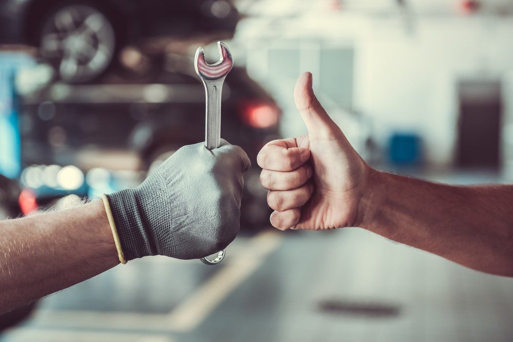 A Mechanic Is Giving a Thumbs up While Holding a Wrench — Bob Kolln Automotive Services in Charmhaven, NSW