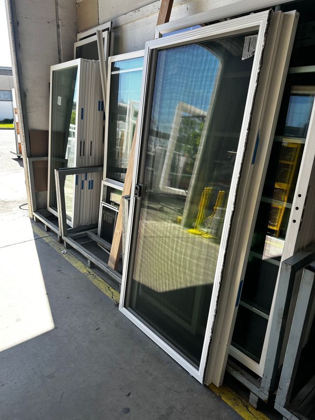 A bunch of windows are stacked on top of each other in a warehouse.