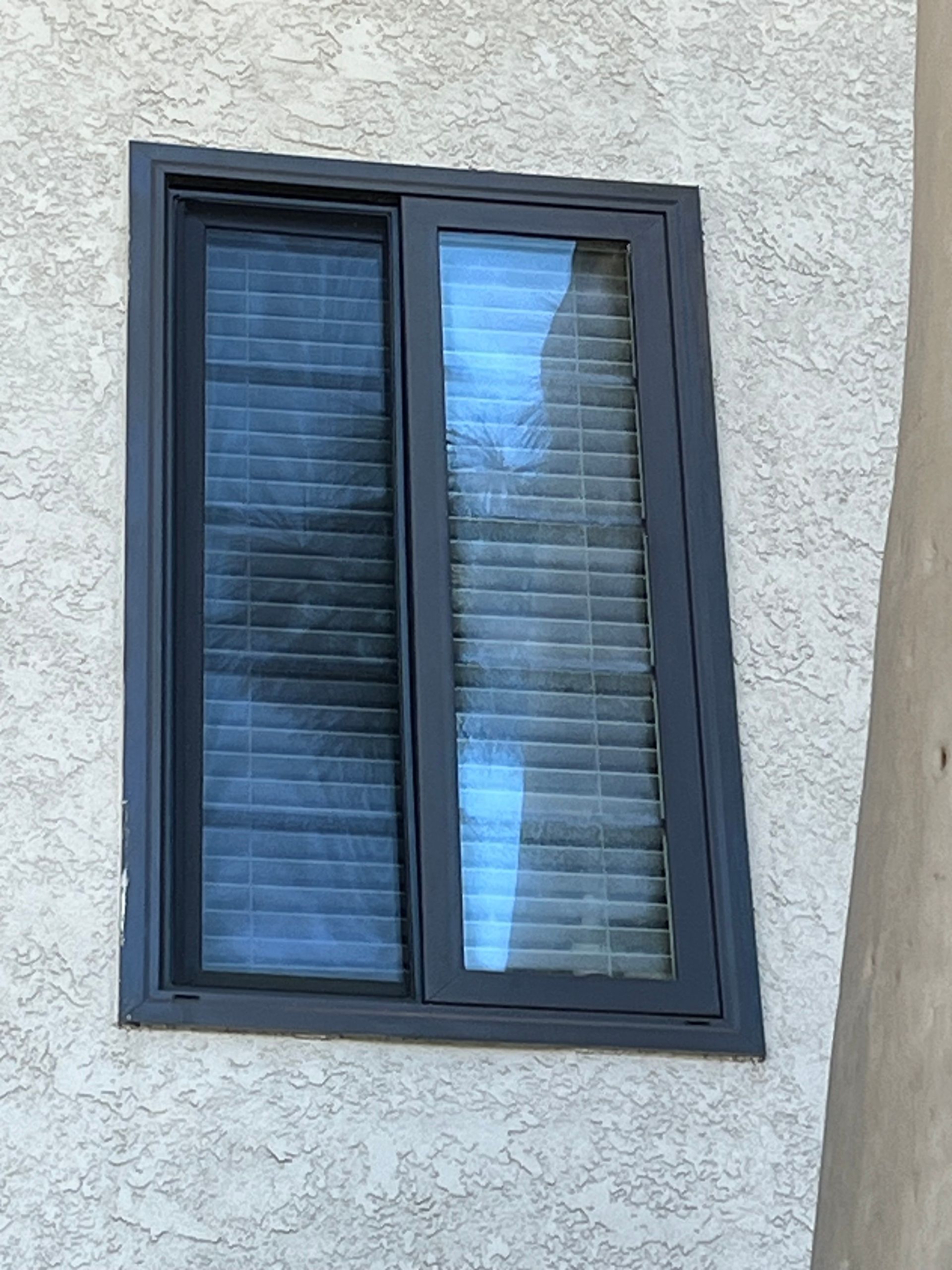 A window with blinds on it is on the side of a building.